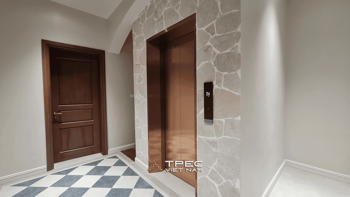 Cửa thang máy inox đồng ốp đá bên sàn lát caro trắng đen tại biệt thự 450kg