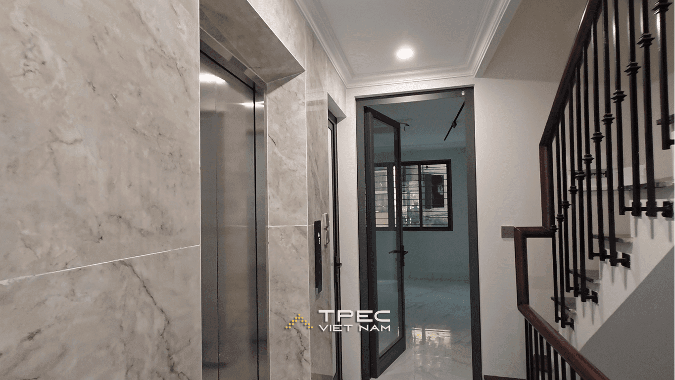 Sảnh thang máy inox ốp đá cạnh cầu thang lan can sắt nhà phố Nguyễn Công Hoan
