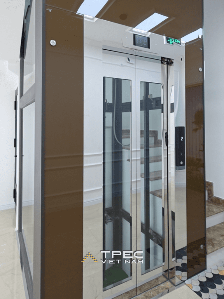 Cửa thang máy kính khung nâu đồng cạnh cầu thang tòa văn phòng tại Mỹ Đình