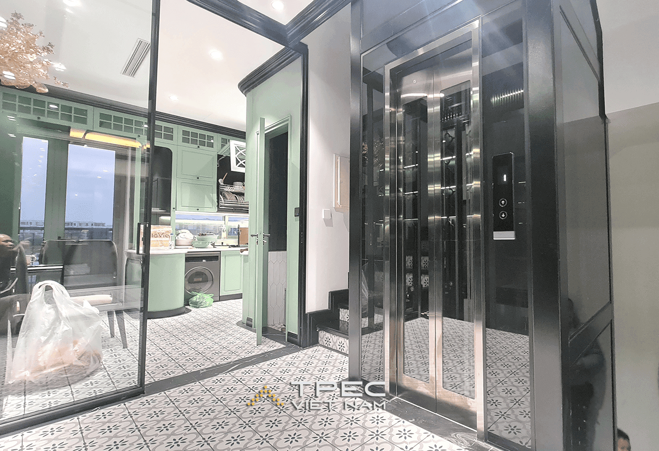 Thang máy kính inox đặt cạnh gian bếp xanh pastel, nhà liền kề The Manor Hà Nội
