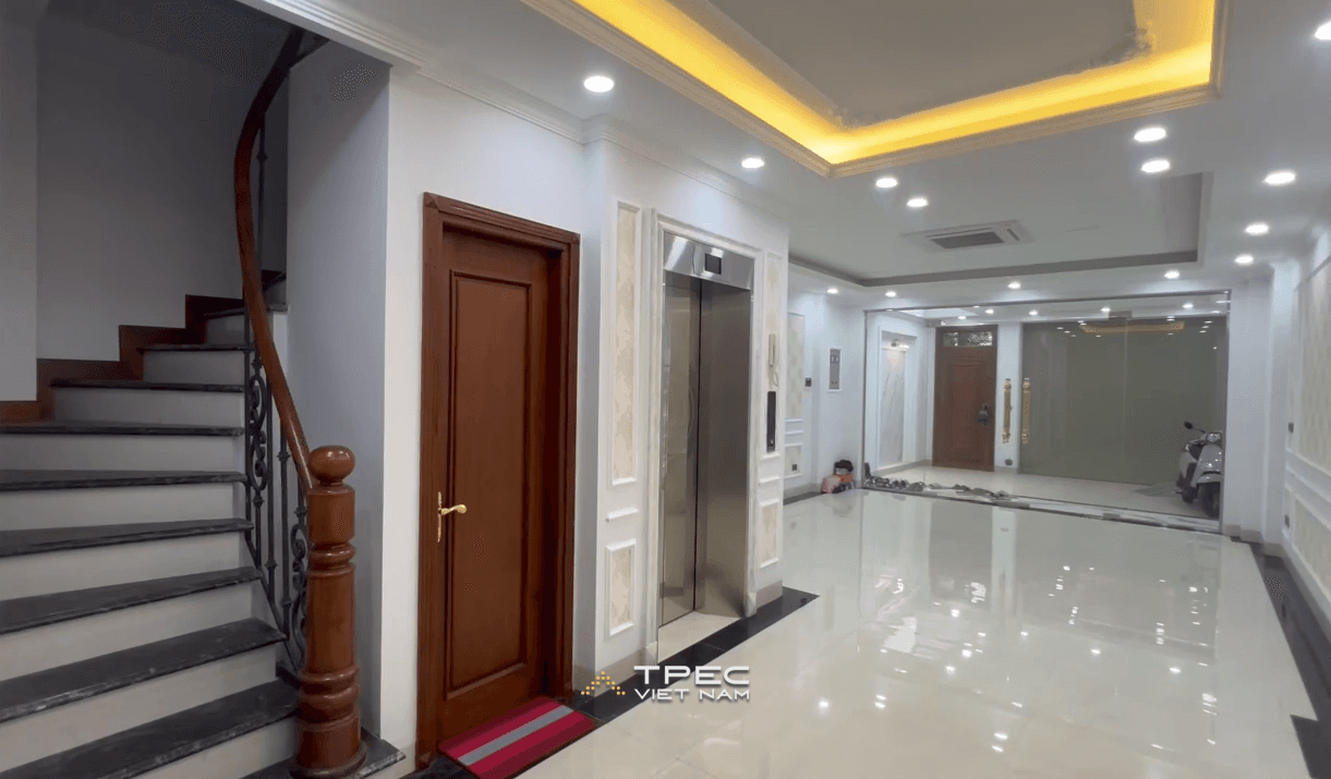 Thang máy gia đình inox cạnh cầu thang bộ trong sảnh nhà phố dự án VOV