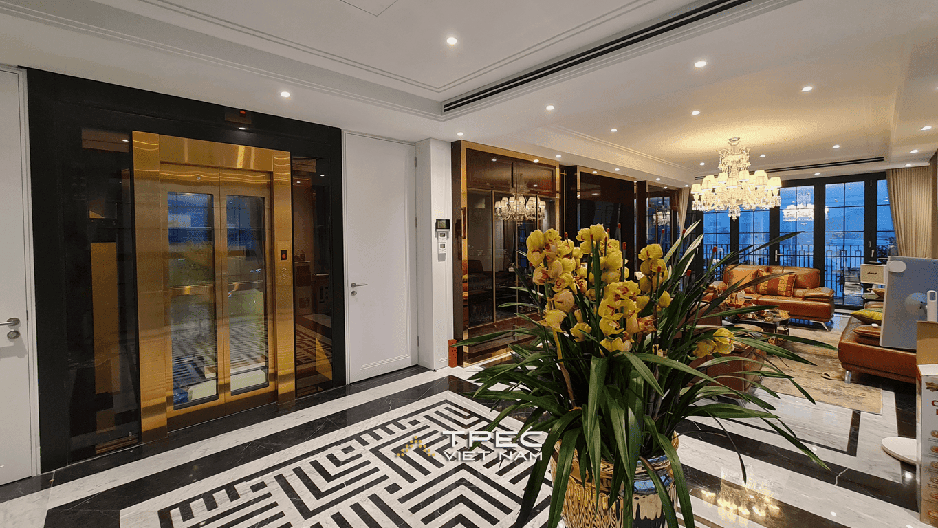 Thang máy kính khung thép đen, cabin inox vàng nhìn ra phòng khách penthouse Tôn Đức Thắng