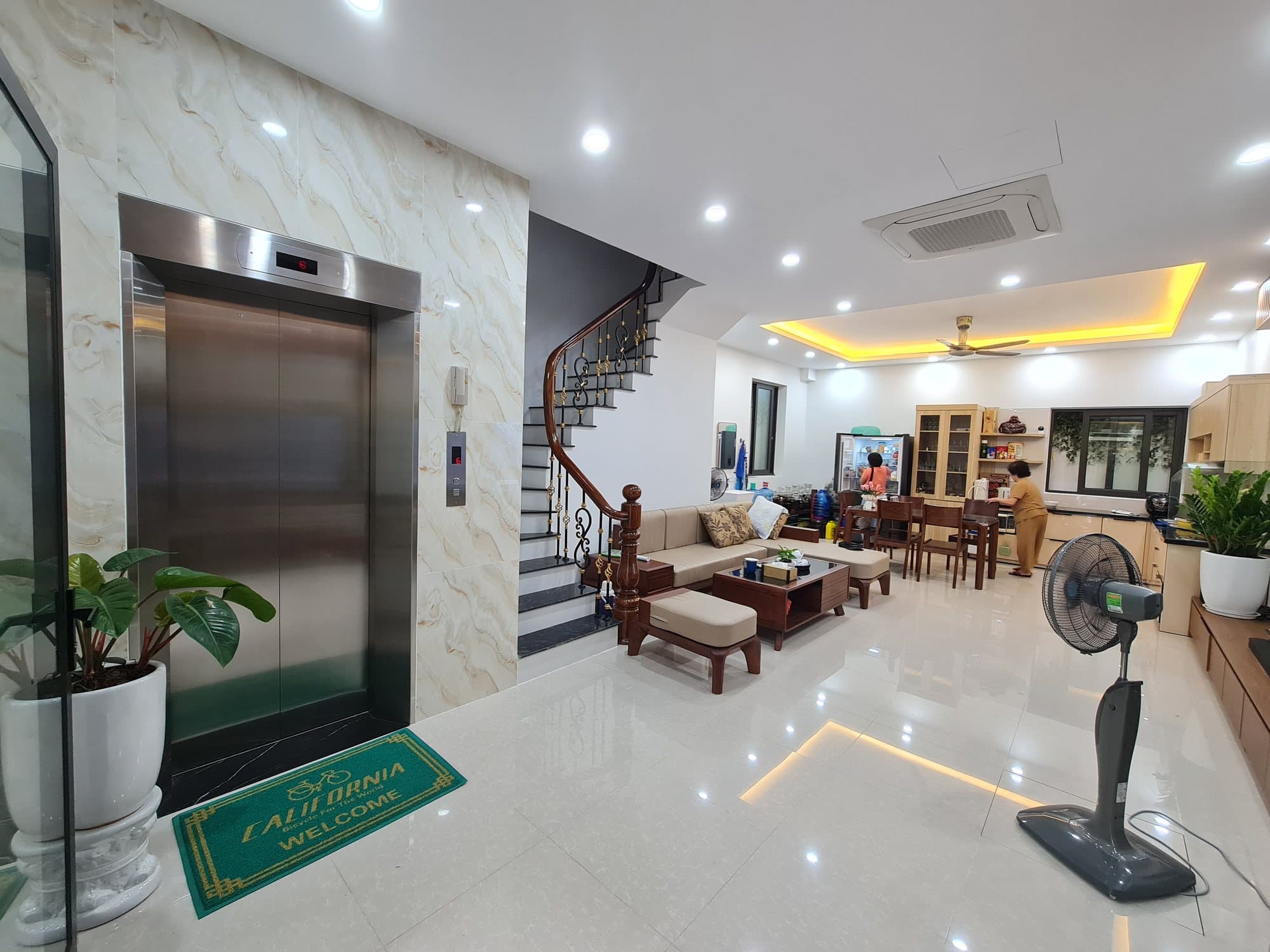 Thang máy gia đình cửa inox trắng ốp đá marble cạnh cầu thang nhà phố