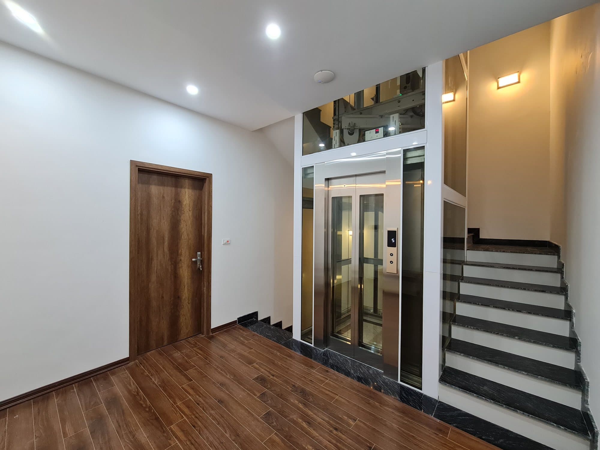 Thang máy kính khung inox trắng tiêu chuẩn trong nhà phố